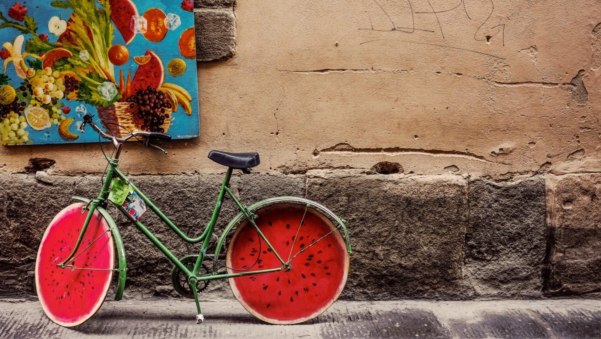 A bicycle with watermelon wheels on the side of a street.