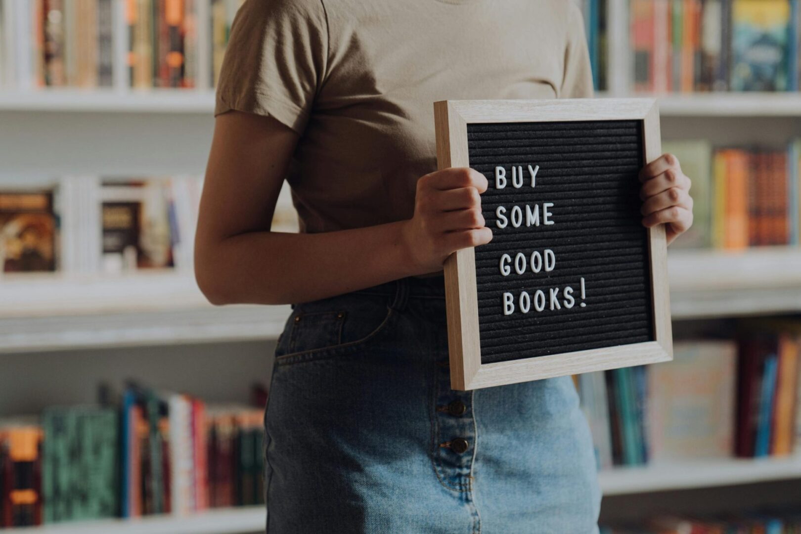 A woman holding a sign that says buy some good books.