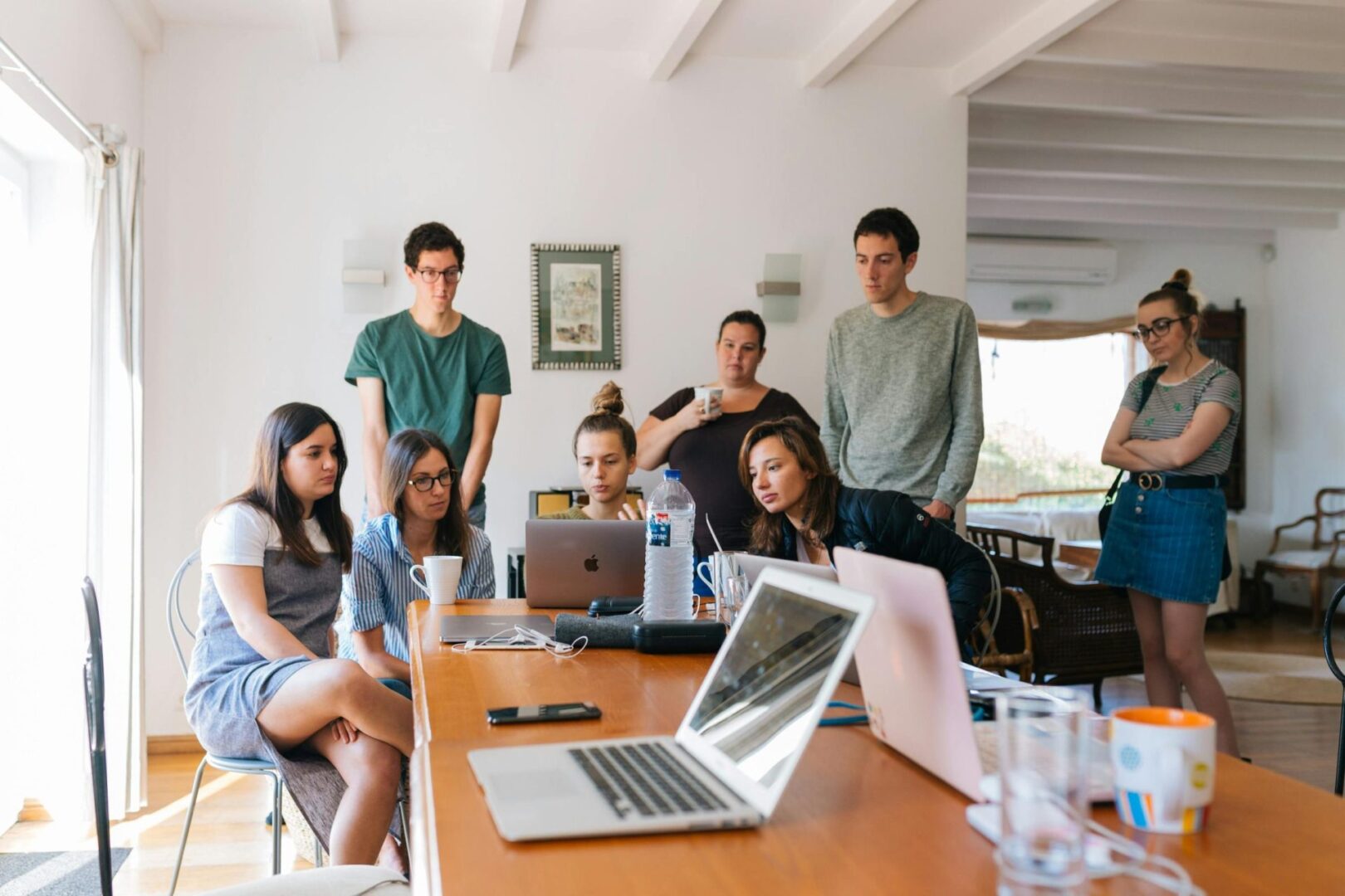 A group of people sitting around a table with laptops.