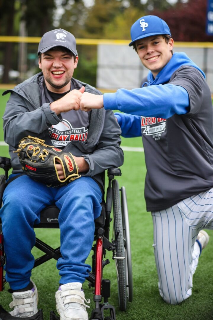 Two men in baseball uniforms are sitting on the grass.